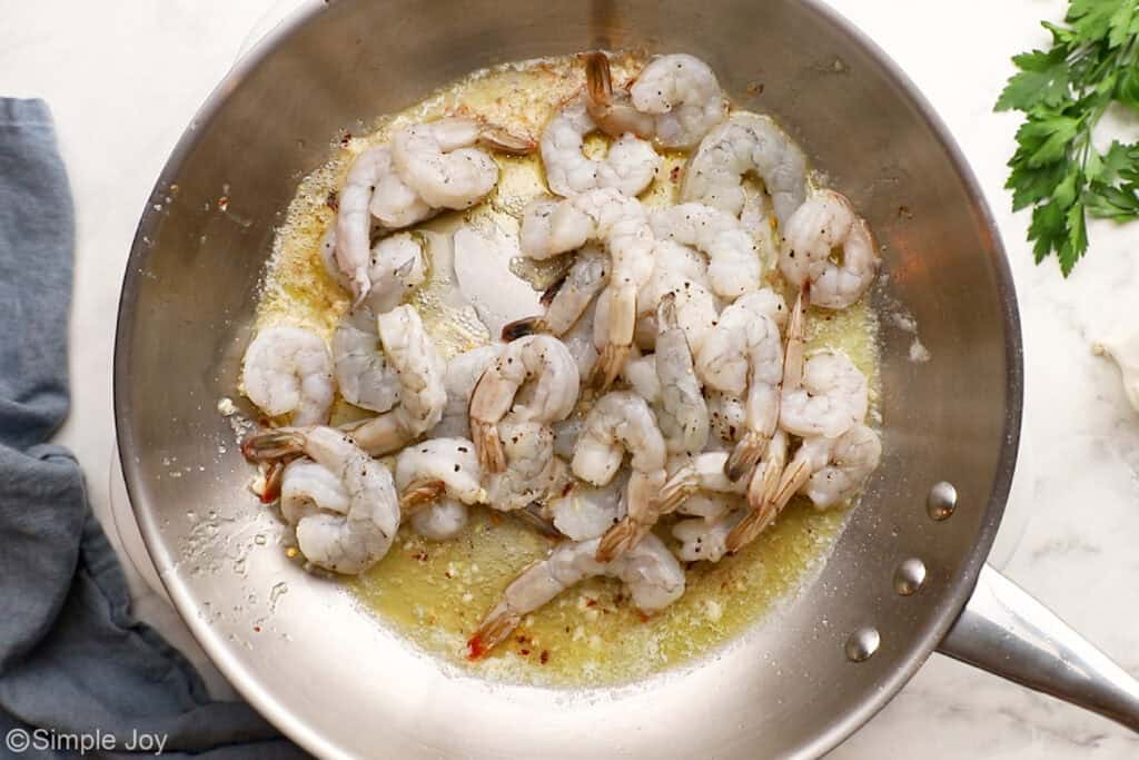 overhead of raw shrimp cooking in a skillet