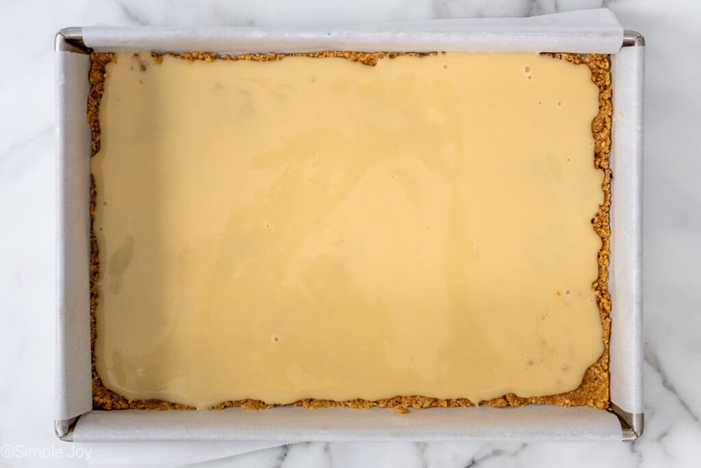 overhead of sweetened condensed milk on a graham cracker crust in a 9 by 13 inch baking dish - 7