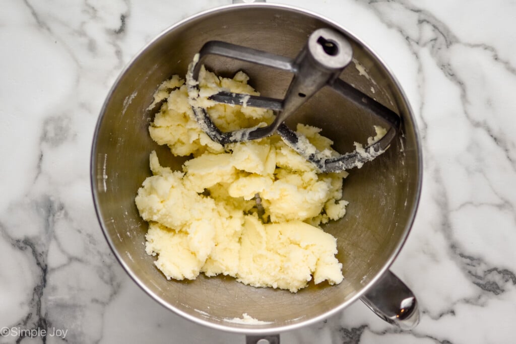 overhead of the bowl of a stand mixer with the paddle attachment and creamed butter and sugar