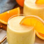 glasses of orange smoothie with orange slices on the rip. Orange and orange slices beside for garnish. - 9