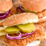 Pork Tenderloin Sandwich garnished with pickles and onions, chips beside - 12