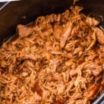 Pinterest graphic for Crock Pot Pulled Pork recipe. Text says, "slow cooker pulled pork simplejoy.com." Image shows a slow cooker of Crock Pot Pulled Pork.