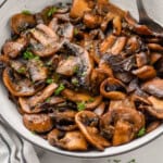 Pinterest graphic for Sautéed Mushrooms recipe. Image shows a bowl of Sautéed Mushrooms with a spoon. Text says, "super easy Sautéed Mushrooms simplejoy.com"