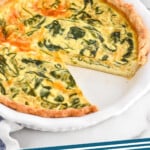 Pinterest graphic for Spinach Quiche recipe. Image shows a Spinach Quiche with a slice missing, cups of coffee and bowl of berries beside. Text says, "Spinach Quiche simplejoy.com."