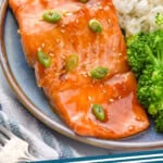 Pinterest graphic for Teriyaki Salmon recipe. Image shows Teriyaki Salmon garnished with green onions and sesame seeds served on a plate with white rice and broccoli. Text says, "Teriyaki Salmon simplejoy.com."