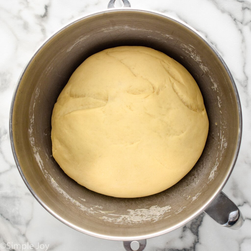 overhead of mixing bowl with cinnamon roll dough as ball risen