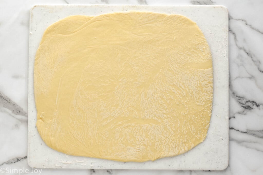 overhead of cutting board with homemade cinnamon roll dough rolled out