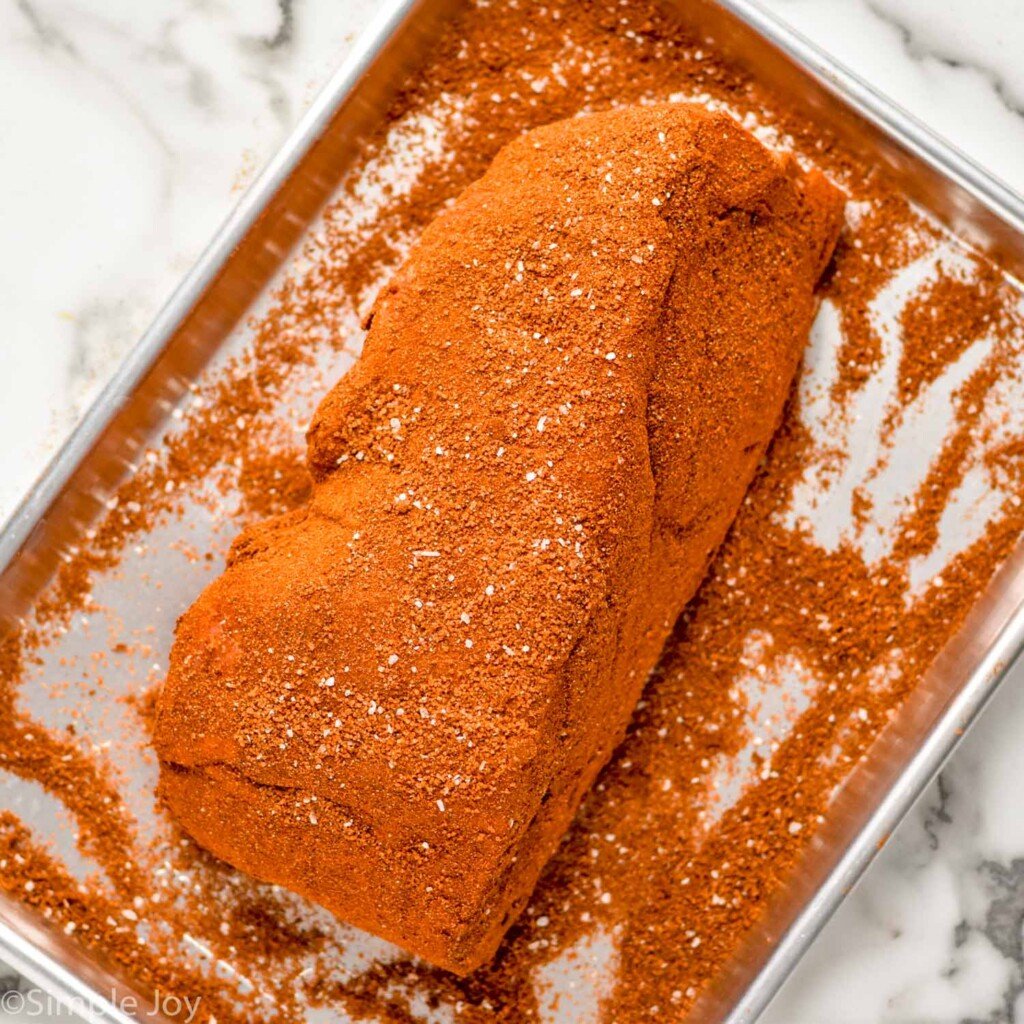 Overhead view of seasoned pork shoulder on baking sheet for Crock Pot Pulled Pork recipe