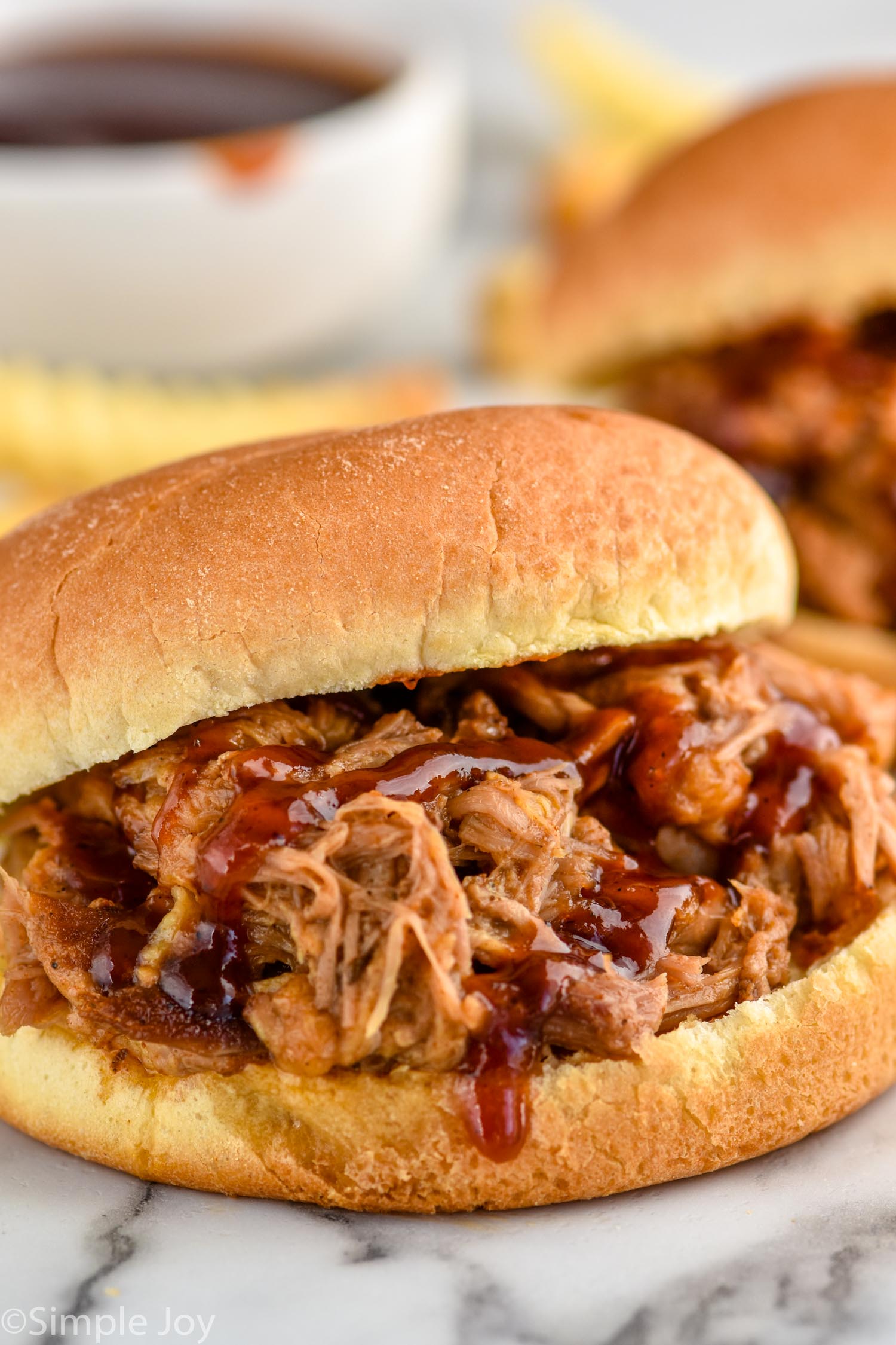 Side view of a Crock Pot Pulled Pork sandwich garnished with bbq sauce