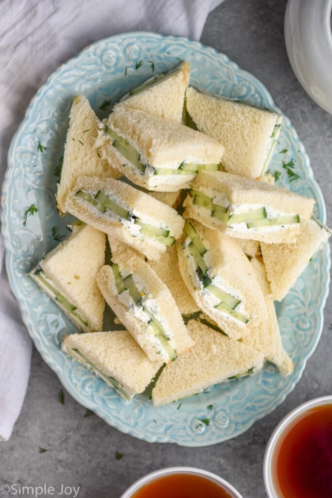 overhead of blue plate of cut cucumber sandwiches