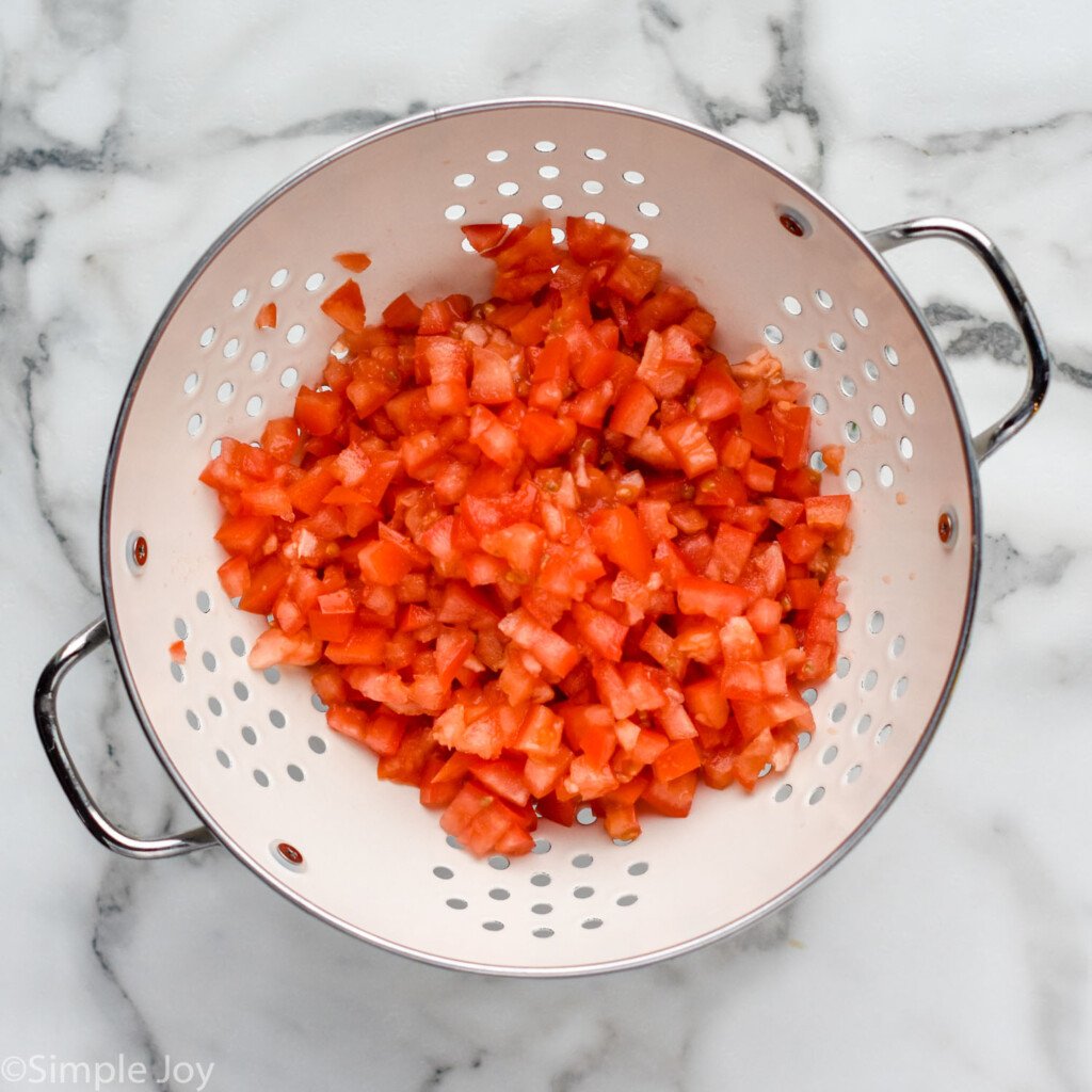 Overhead view of a colander of diced tomatoes for Bruschetta recipe
