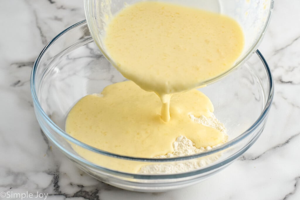 Photo of mixing bowl of wet ingredients being poured into mixing bowl of dry ingredients for batter of Sheet Pan Pancakes recipe.