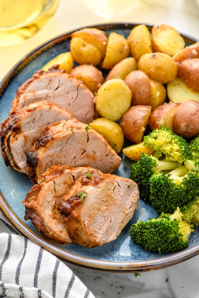 Slices of Air Fryer Pork Tenderloin served on a plate with potatoes and broccoli.