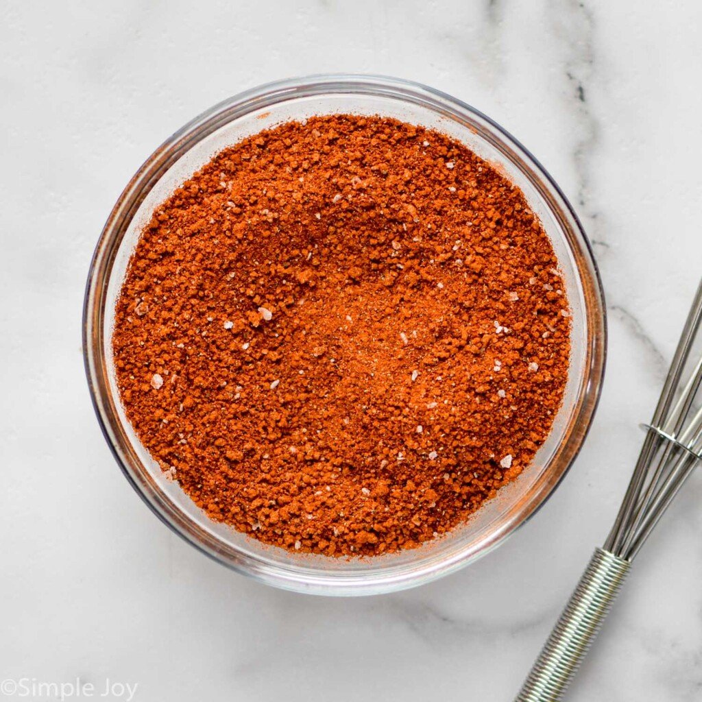 Overhead view of a bowl of seasoning for Crock Pot Pulled Pork recipe with a whisk beside