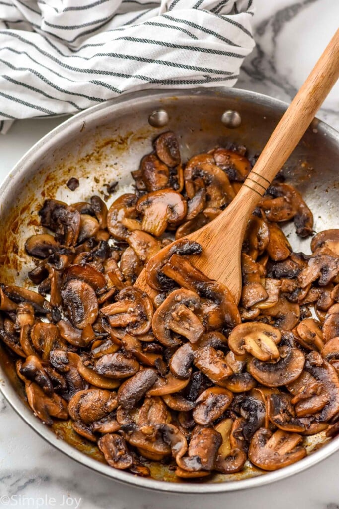 Skillet of Sautéed Mushrooms with a wooden spoon.