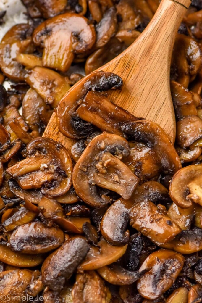 Close up view of Sautéed Mushrooms with a wooden spoon