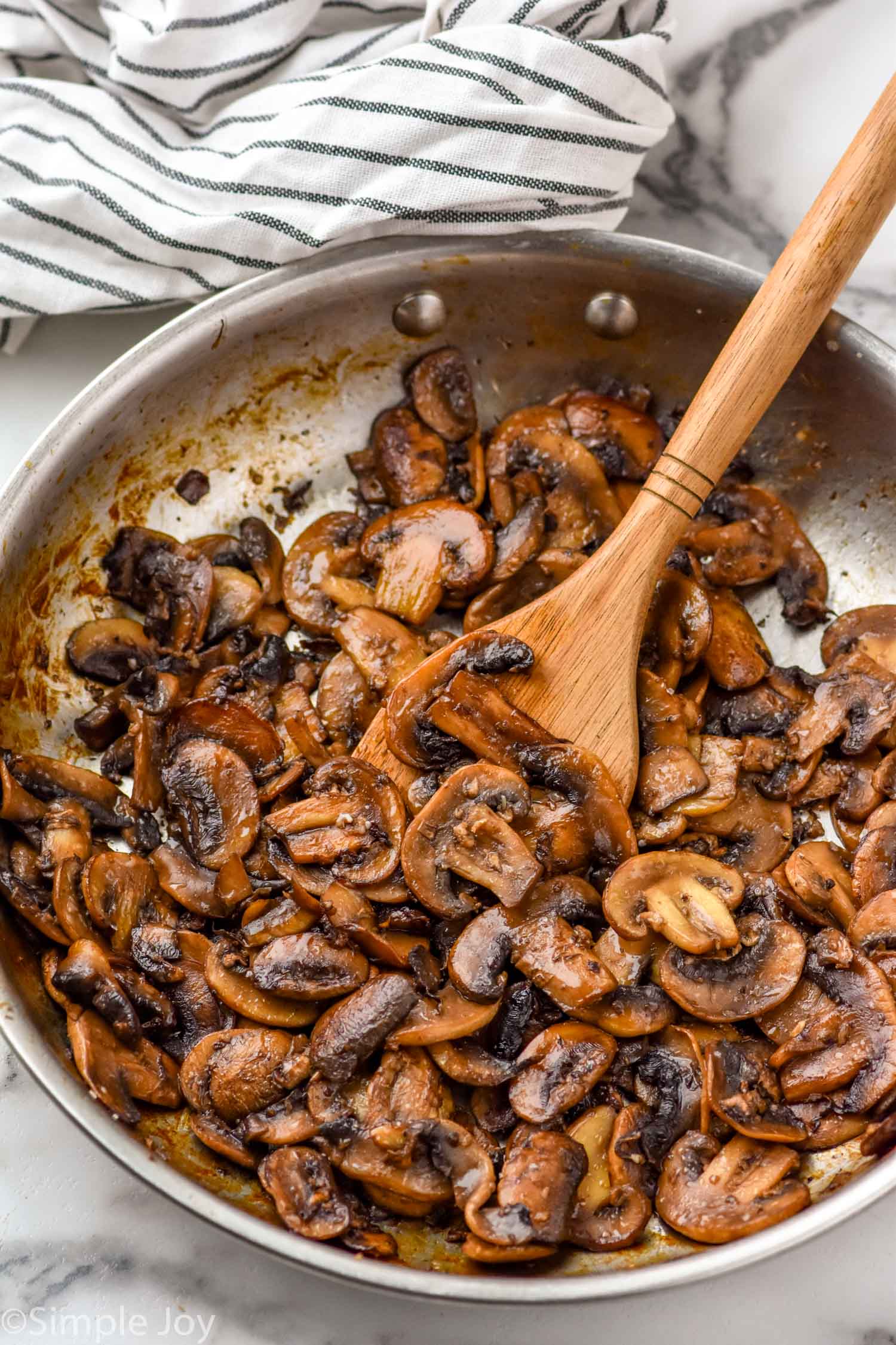 Skillet of Sautéed Mushrooms with a wooden spoon.