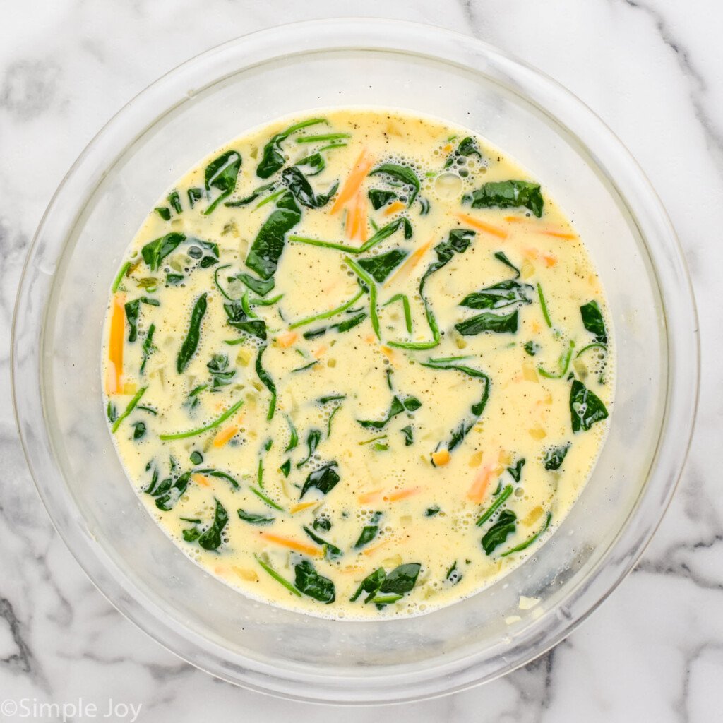 Overhead view of a mixing bowl of egg mixture for Spinach Quiche recipe.