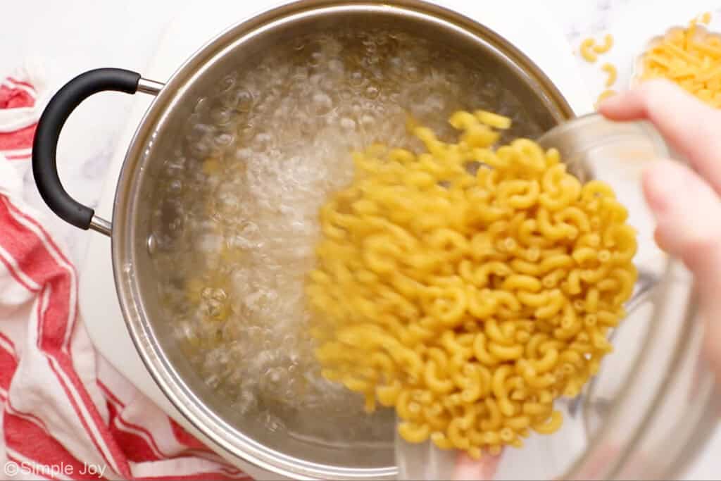 overhead of a pot of boiling water with macaroni being poured in