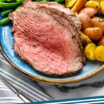 Pinterest graphic for Sirloin Tip Roast recipe. Image shows a plate with slices of Sirloin Tip Roast with green beans and potatoes. Text says, "Sirloin Tip Roast simplejoy.com."