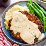 Chicken Fried Steak topped with country gravy on a plate with mashed potatoes and green beans - 11