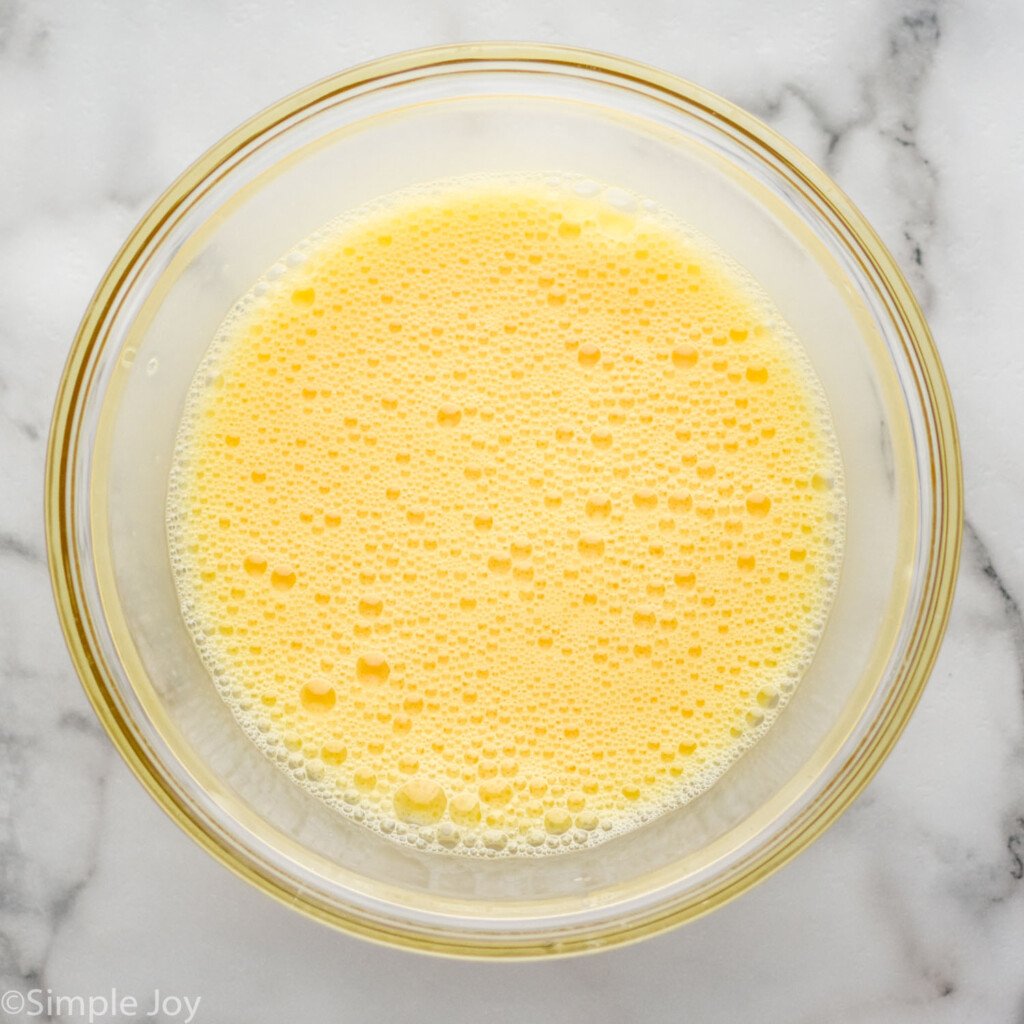 overhead of glass bowl of whisked eggs for Scrambled Eggs