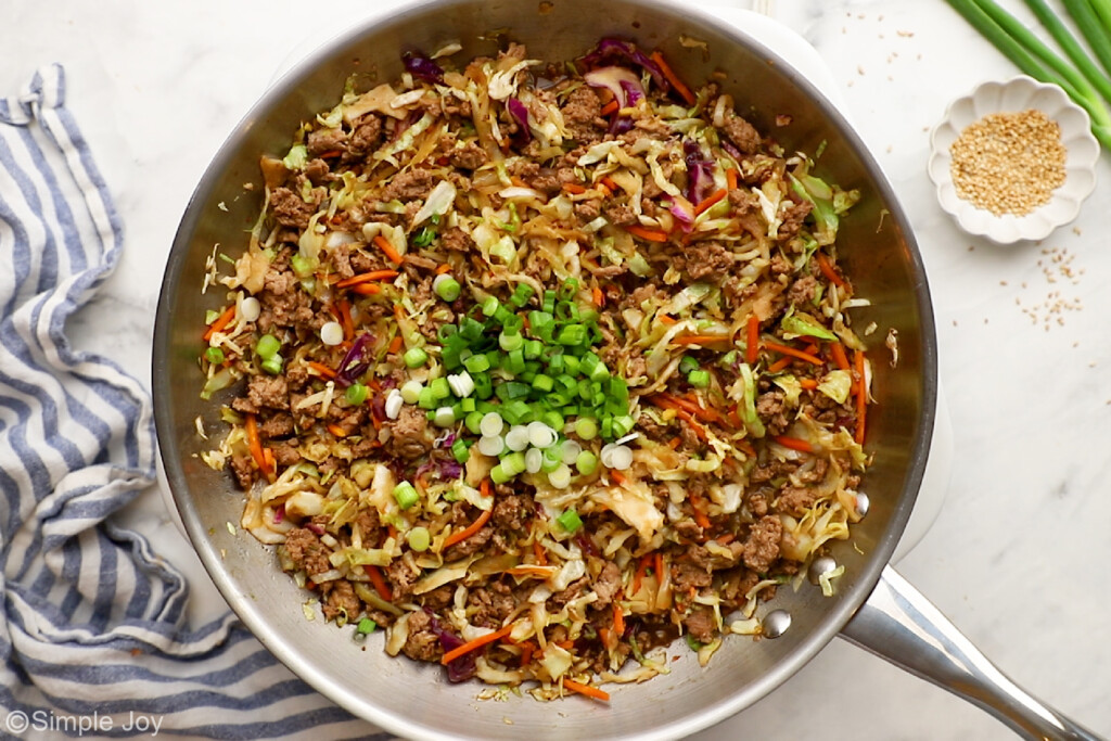 skillet with cooked ground turkey, and coleslaw, and fresh green onions added