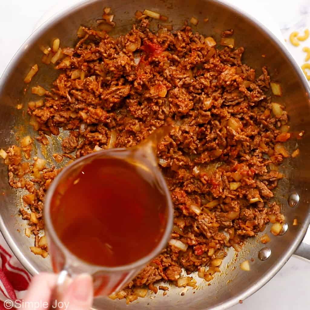 pouring beef broth into a skillet of ground beef