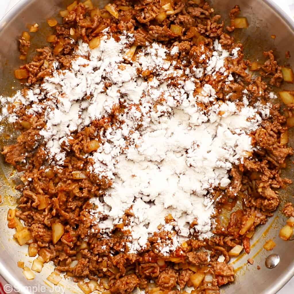 adding flour to a skillet of ground beef