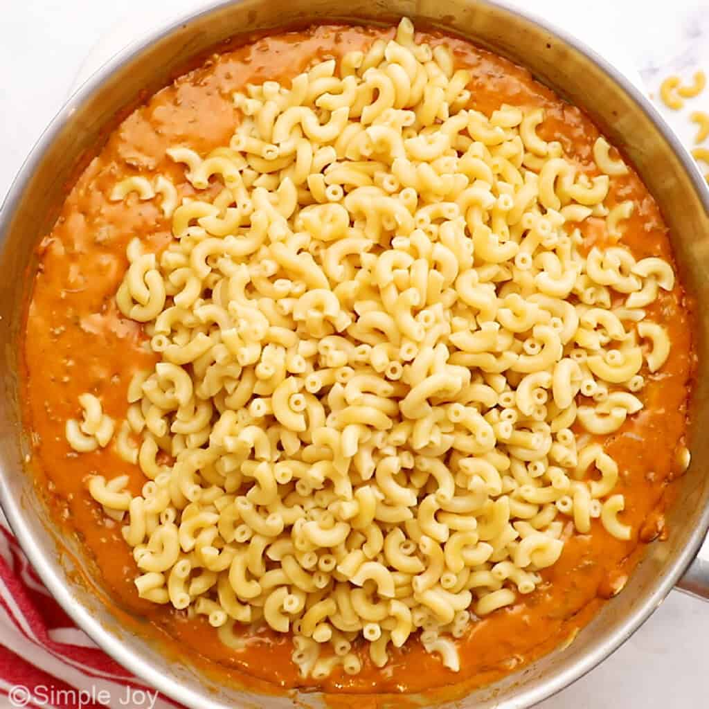 cooked pasta being added to a sauce