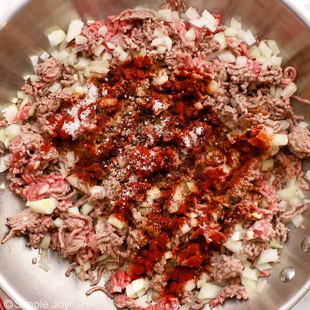 seasonings added to ground beef, onion, and garlic in a skillet