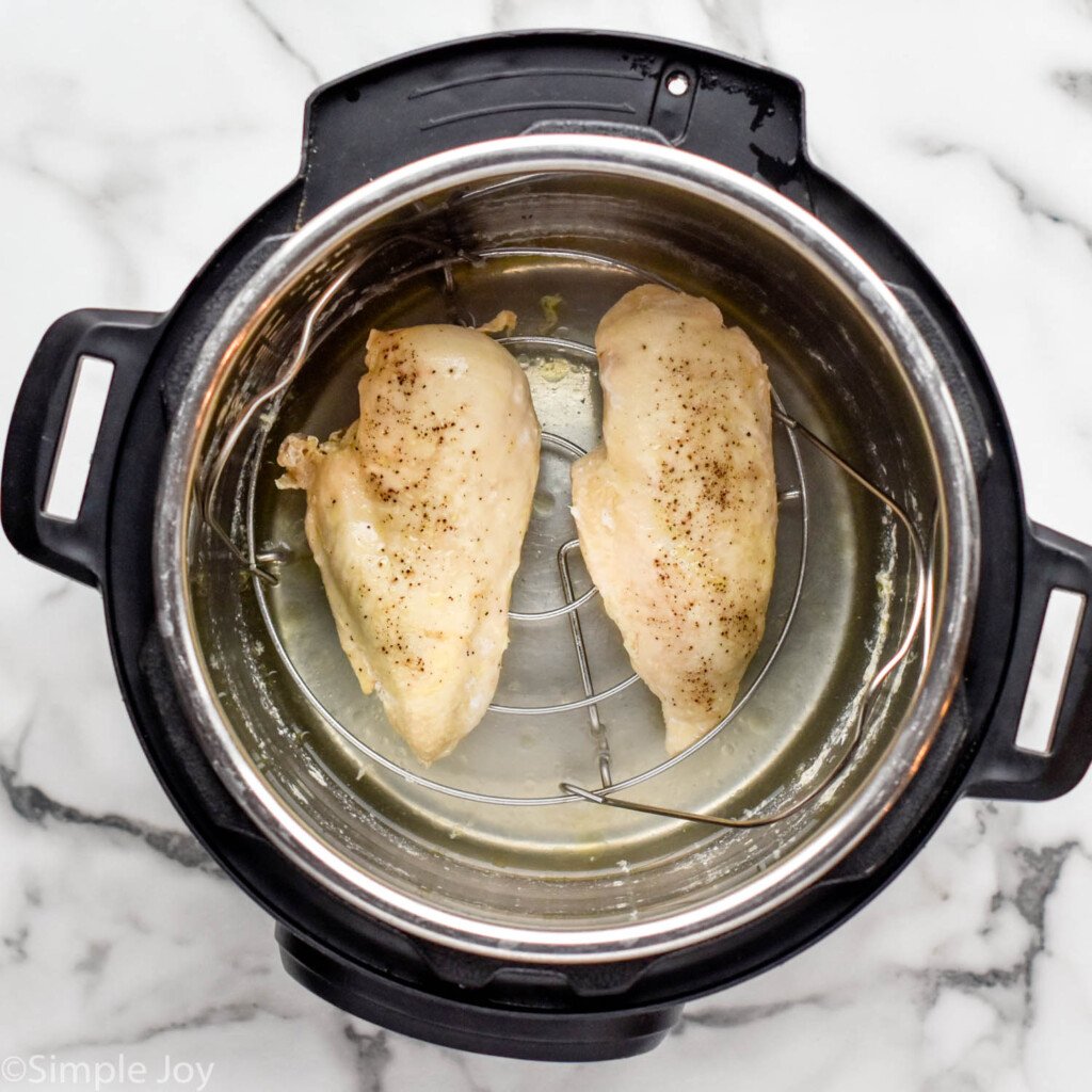 Overhead view of two cooked chicken breasts in an instant pot for Instant Pot Chicken recipe.