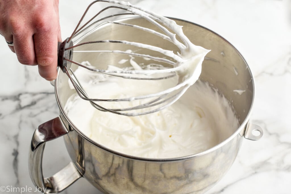 man's hand holding whisk attachment with mixing bowl of meringue underneath to make Lemon Meringue Pie