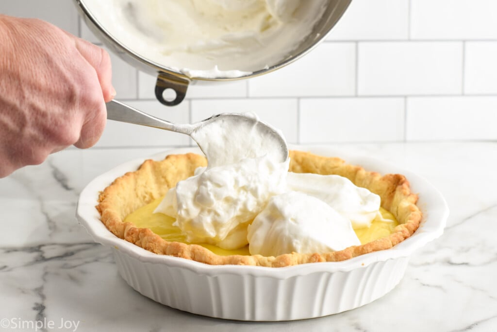 man's hand holding spoon to scoop meringue from mixing bowl into Lemon Meringue Pie with a spoon