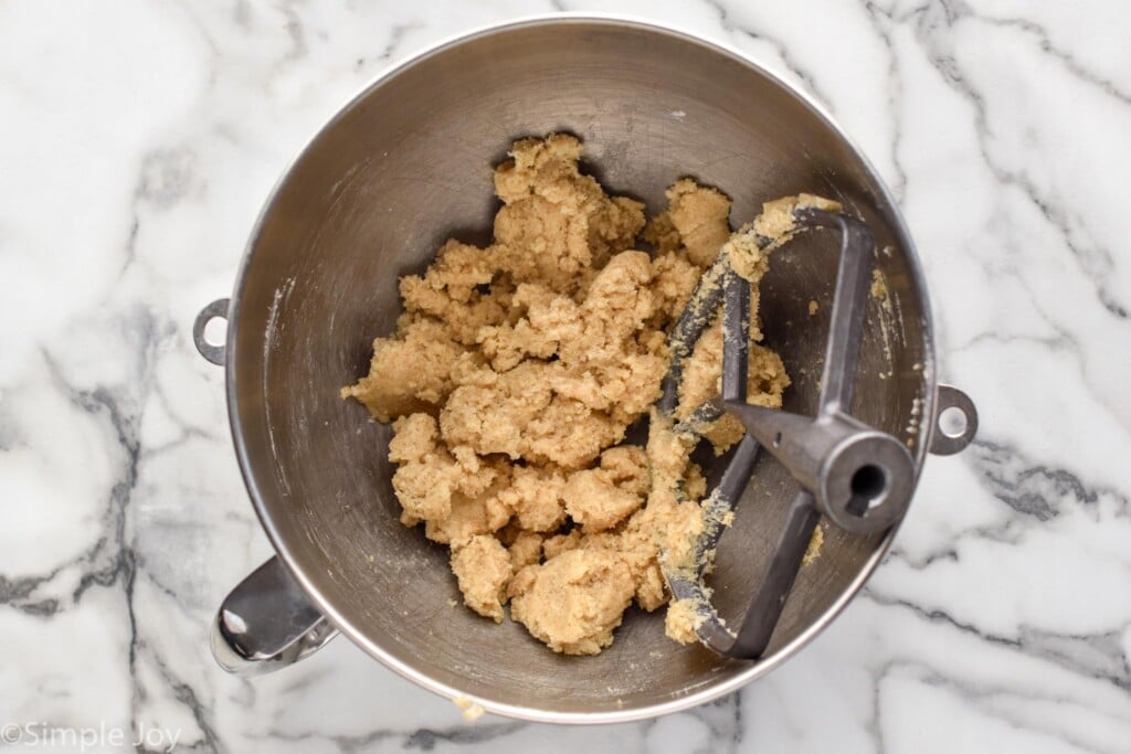 overhead of mixing bowl of oatmeal cookie dough and paddle attachment
