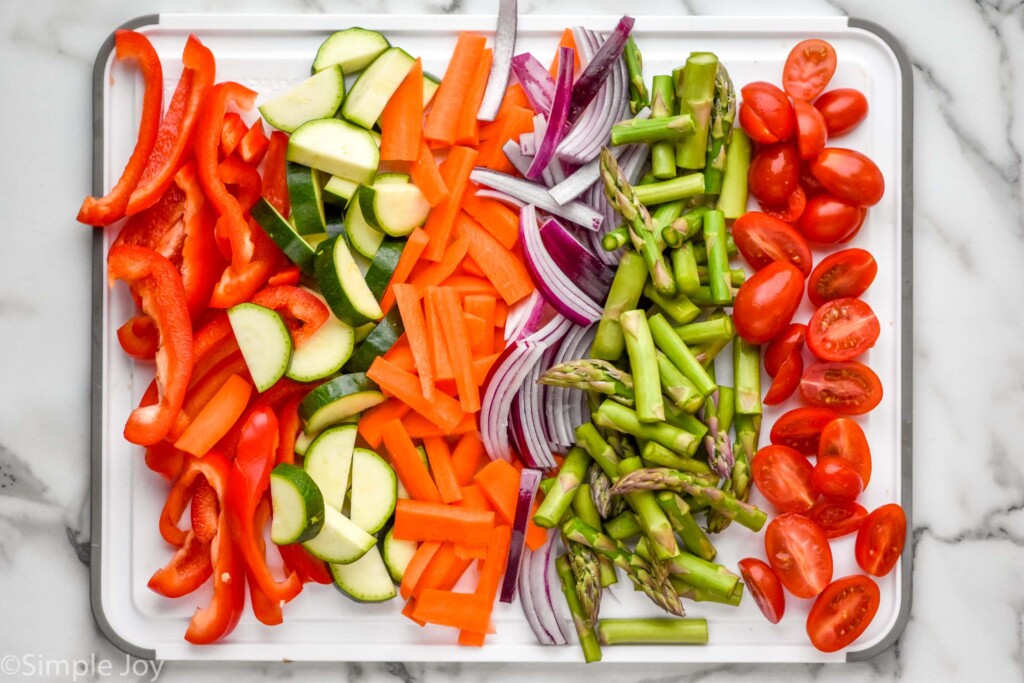 Overhead view of a cutting board of chopped vegetables for Pasta Primavera recipe.