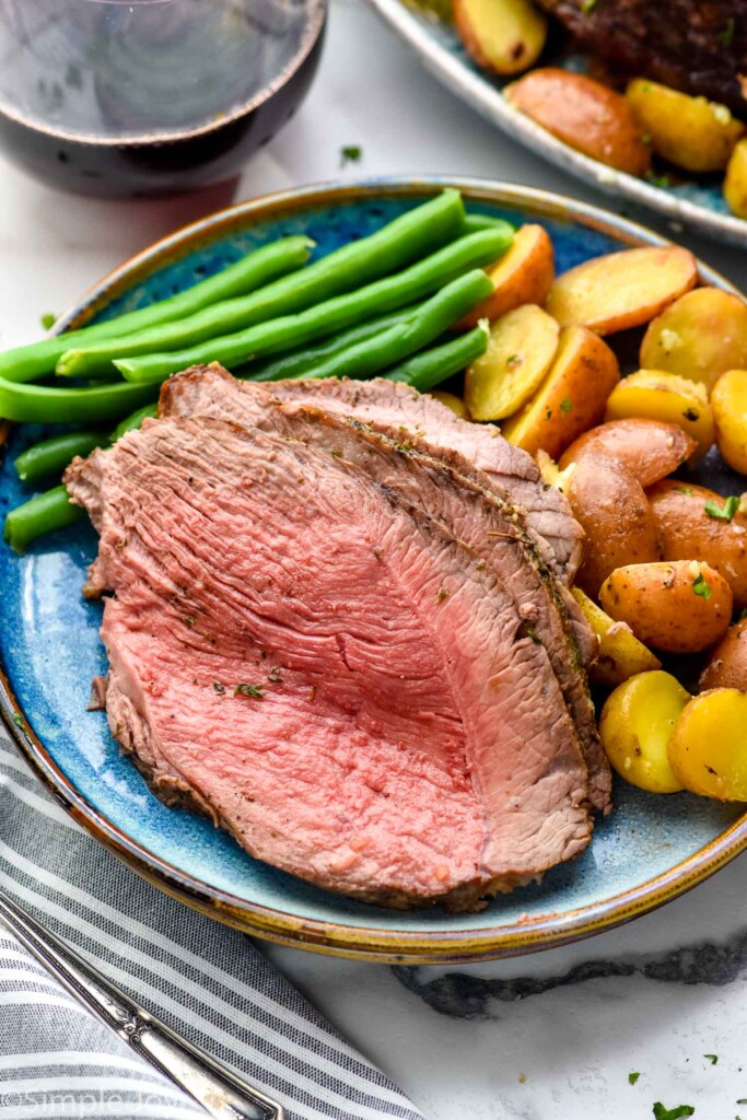 Plate with slices of Sirloin Tip Roast with green beans and potatoes.