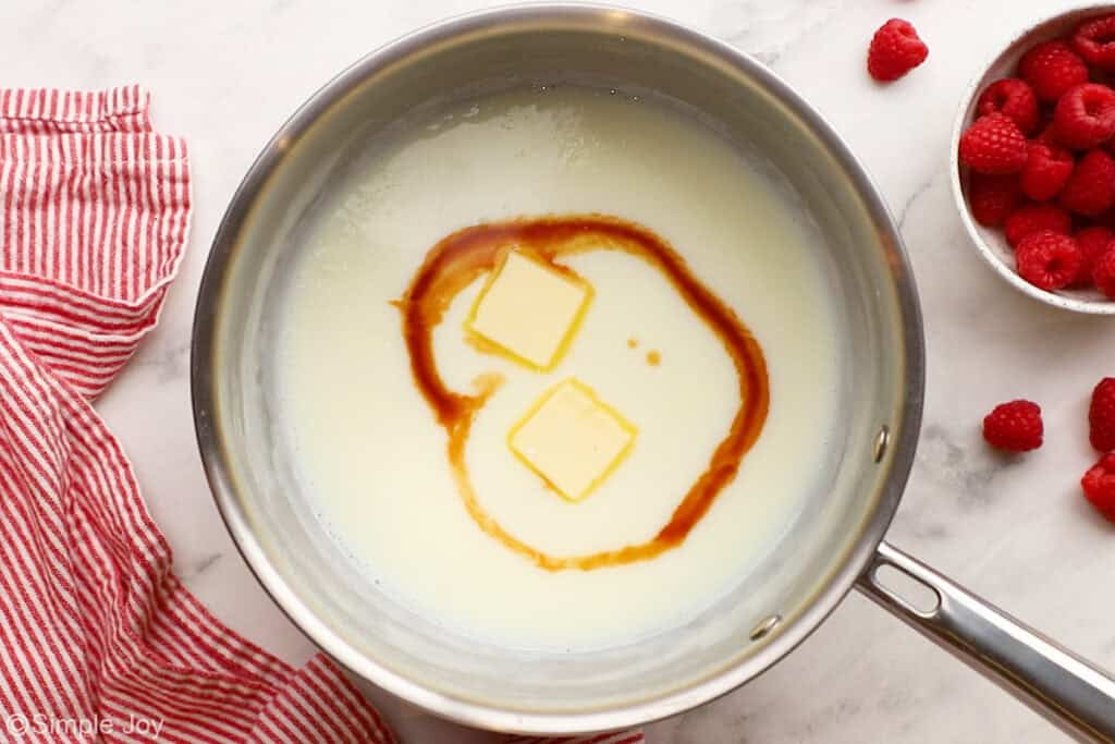 overhead of a saucepan with two pats of butter and vanilla extract added to a milk mixture to make vanilla pudding
