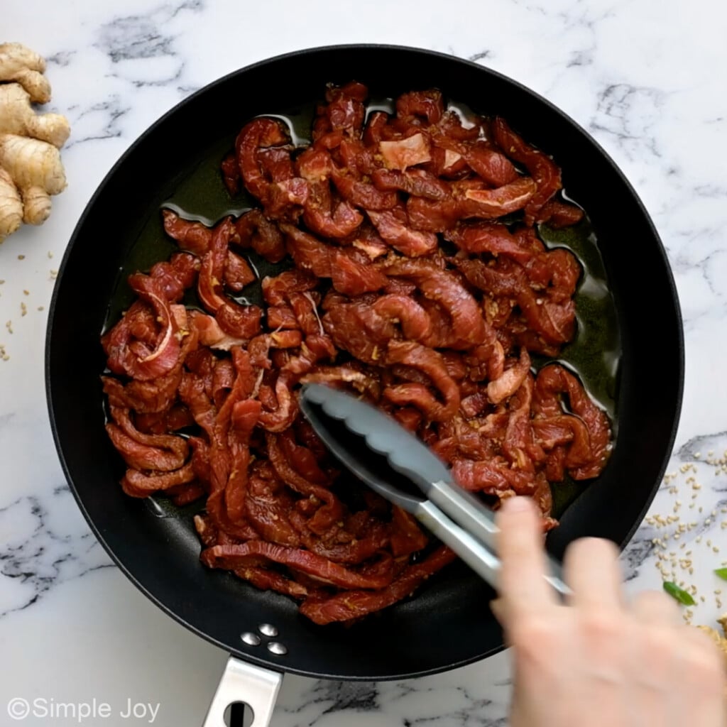 cut up skirt steak being cooked in a skillet
