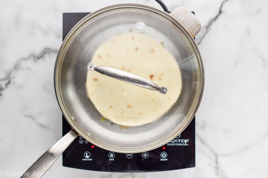 Beef quesadilla in a skillet with a lid