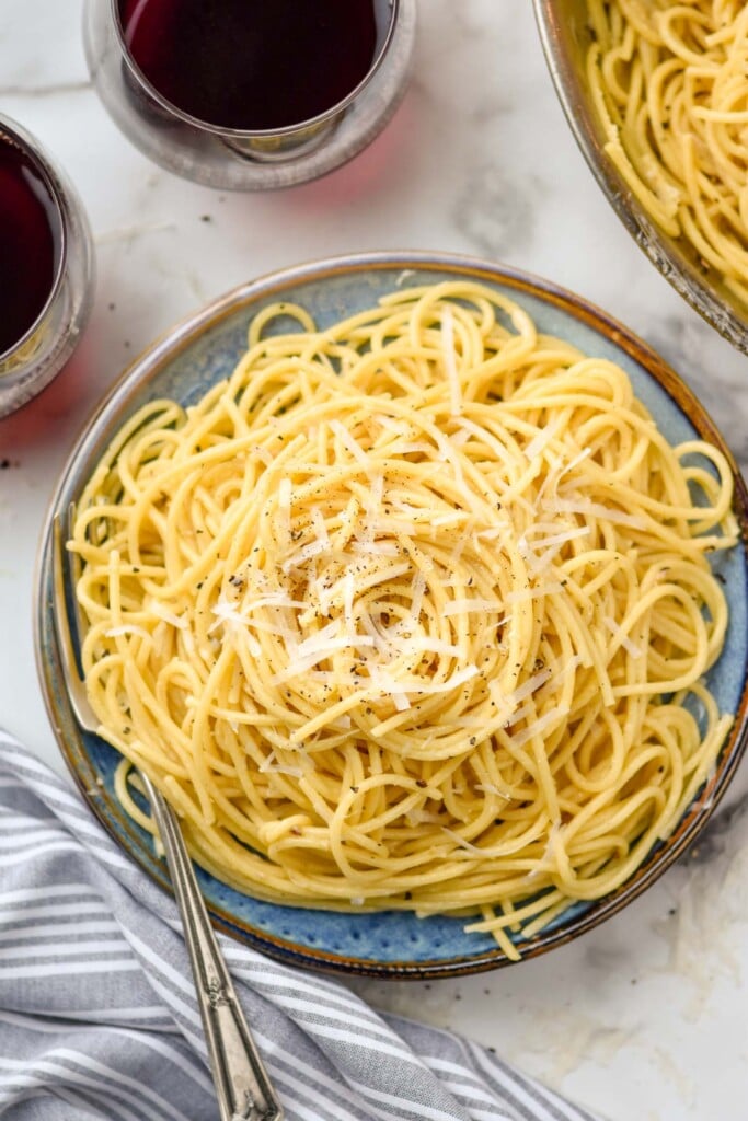 overhead of plate of Cacio E Pepe topped with black pepper and grated cheese.