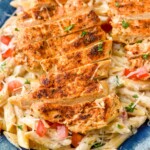Close up view of Creamy Cajun Chicken Pasta served on a plate with shredded parmesan cheese and parsley.