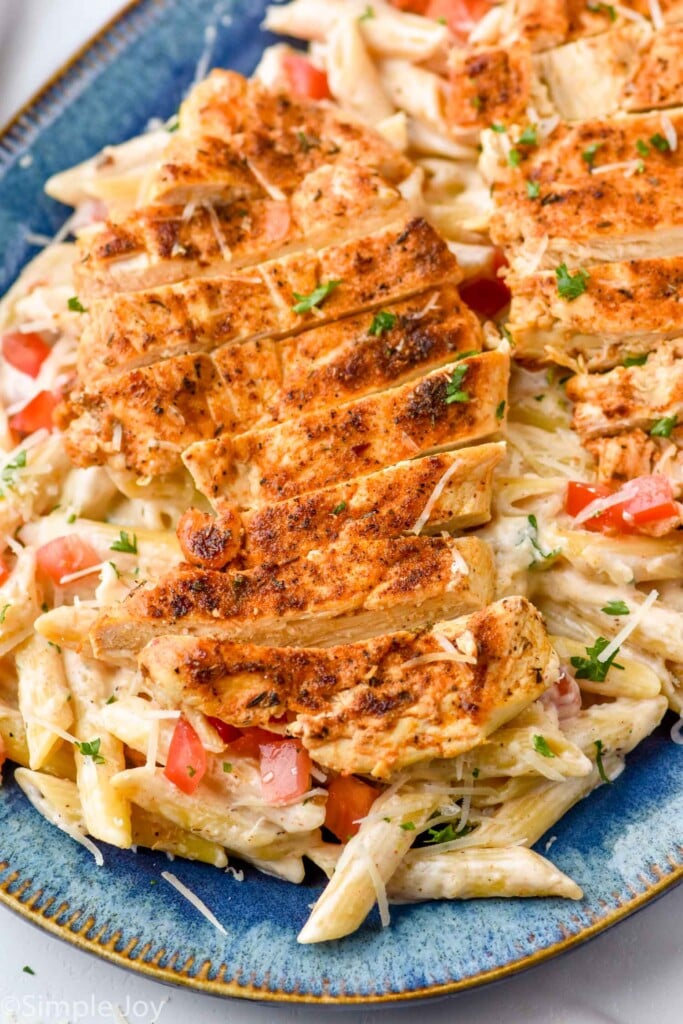 Close up view of Creamy Cajun Chicken Pasta served on a plate with shredded parmesan cheese and parsley.