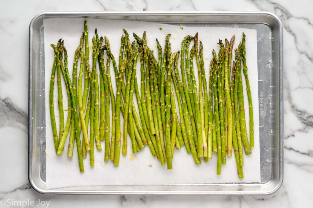 overhead of uncooked asparagus on a rimmed baking sheet lined with parchment paper