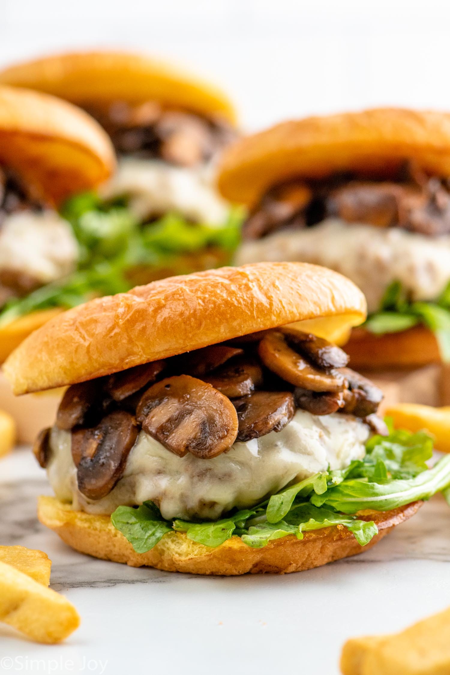 Mushroom Swiss Burger on bun with lettuce. Mushroom Swiss Burgers sitting behind