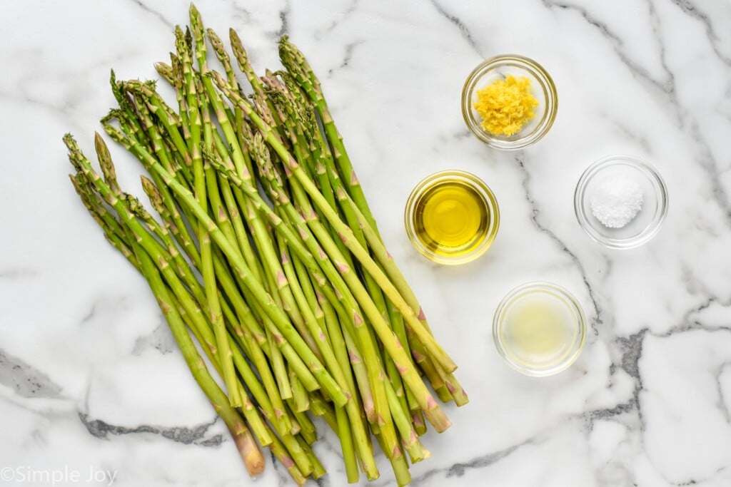 overhead of ingredients for roasted asparagus, fresh asparagus, olive oil, lemon zest, kosher salt, and lemon juice