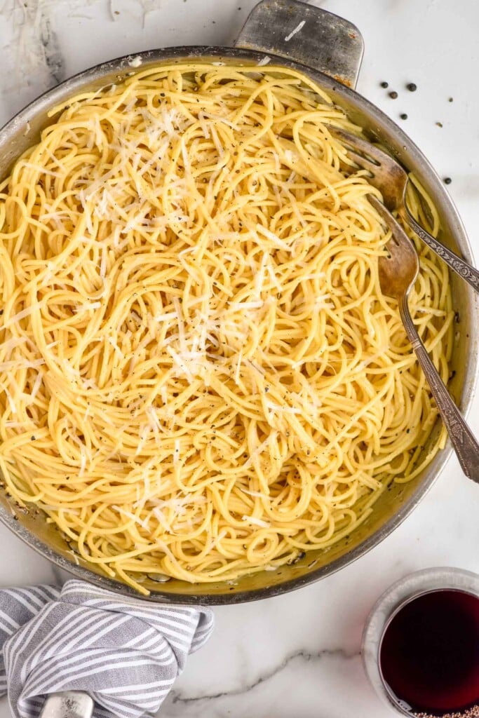 Overhead of skillet of Cacio E Pepe topped with black pepper and grated cheese.