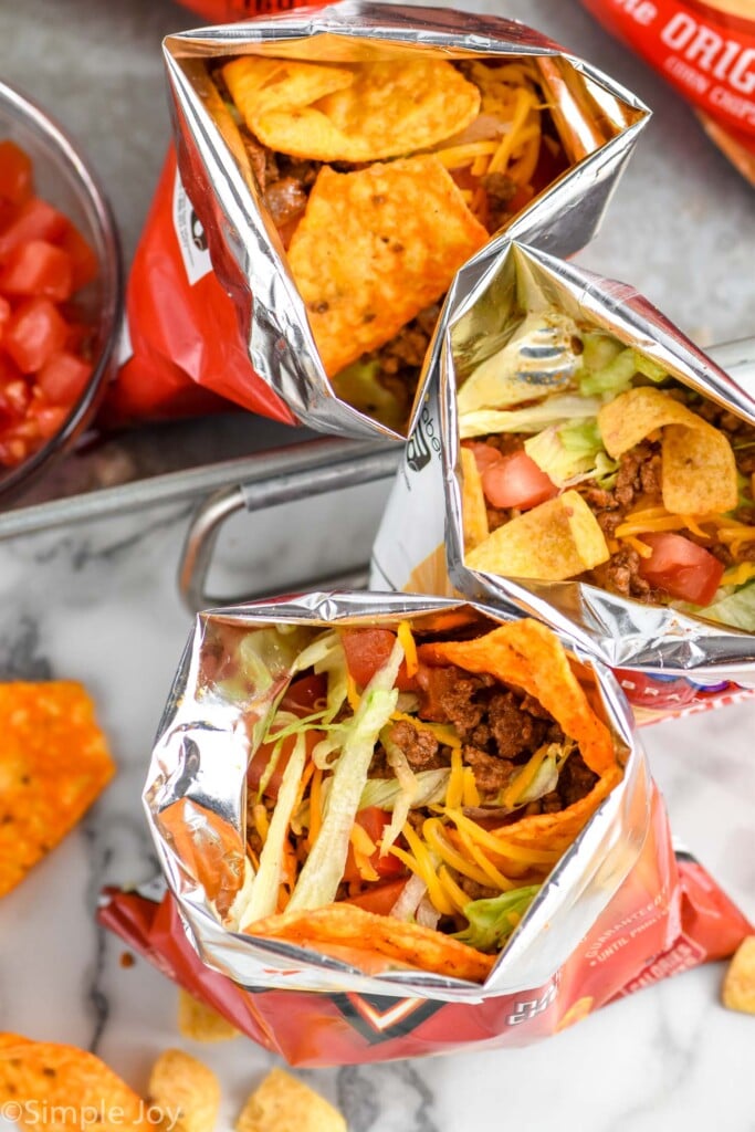 Overhead of chip bags of Walking Tacos of chips, taco meat, shredded cheese, and shredded lettuce