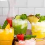 Pinterest graphic for agua fresca recipe. Text says, "refreshing agua fresca recipe simplejoy.com." Image shows four flavors of Agua Fresca drinks served in glasses with fruit and mint leaves as garnish. More fruit and mint leaves on the counter for garnish.