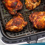 Pinterest graphic for Air Fryer Chicken Thighs recipe. Image is overhead view of Air Fryer Chicken Thighs in air fryer basket. Text says, "Air Fryer Chicken Thighs simplejoy.com."